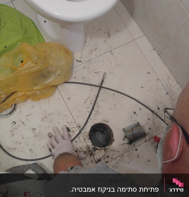 אינסטלטור עובד עם קפיץ ניקוי ליד אסלה